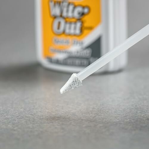 Close-up of a correction fluid brush with a bottle in the background.