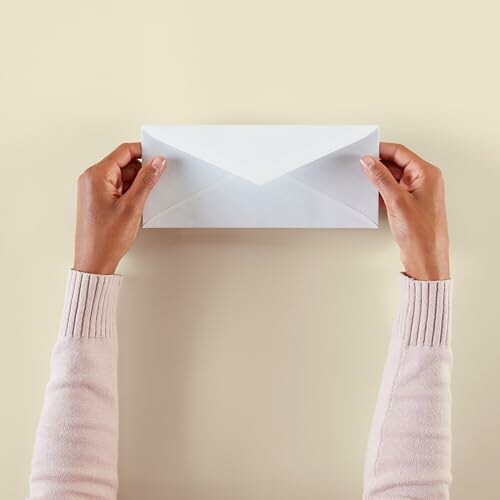 Hands holding a white envelope with a blue patterned interior.