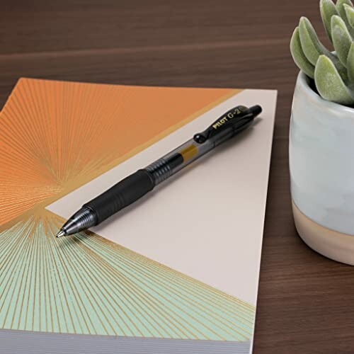 Pen on a colorful notebook with a potted plant nearby.
